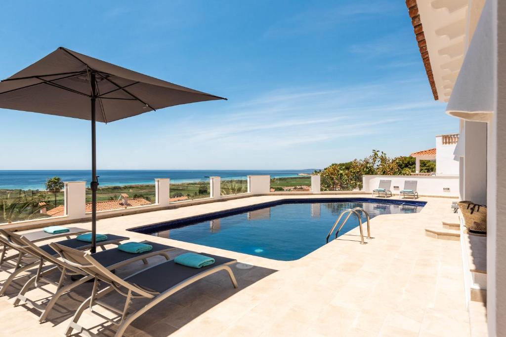 a swimming pool with two chairs and an umbrella at Villa Atalis in Menorca