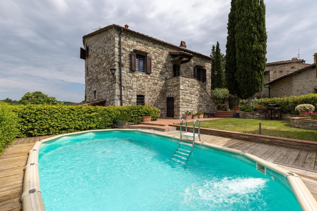 an outdoor swimming pool in front of a stone house at La Petrosa in Radda in Chianti