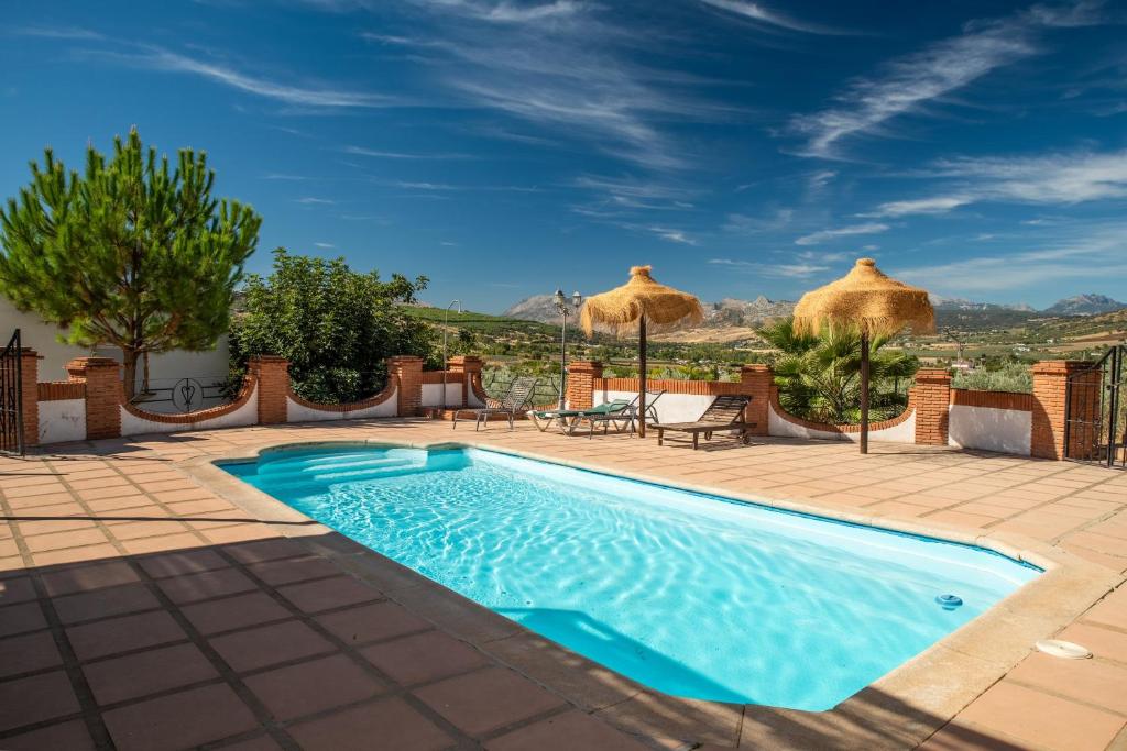 a swimming pool with umbrellas on a patio at Villa Minerva in Ronda