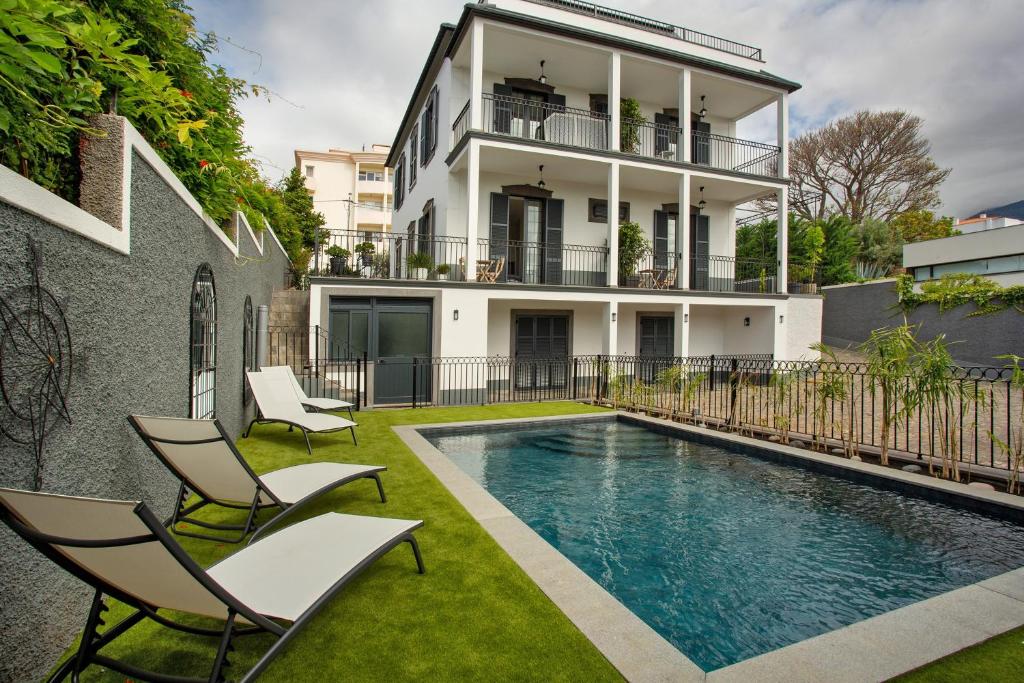 an image of a house with a swimming pool and chairs at Vila Francisco in Funchal