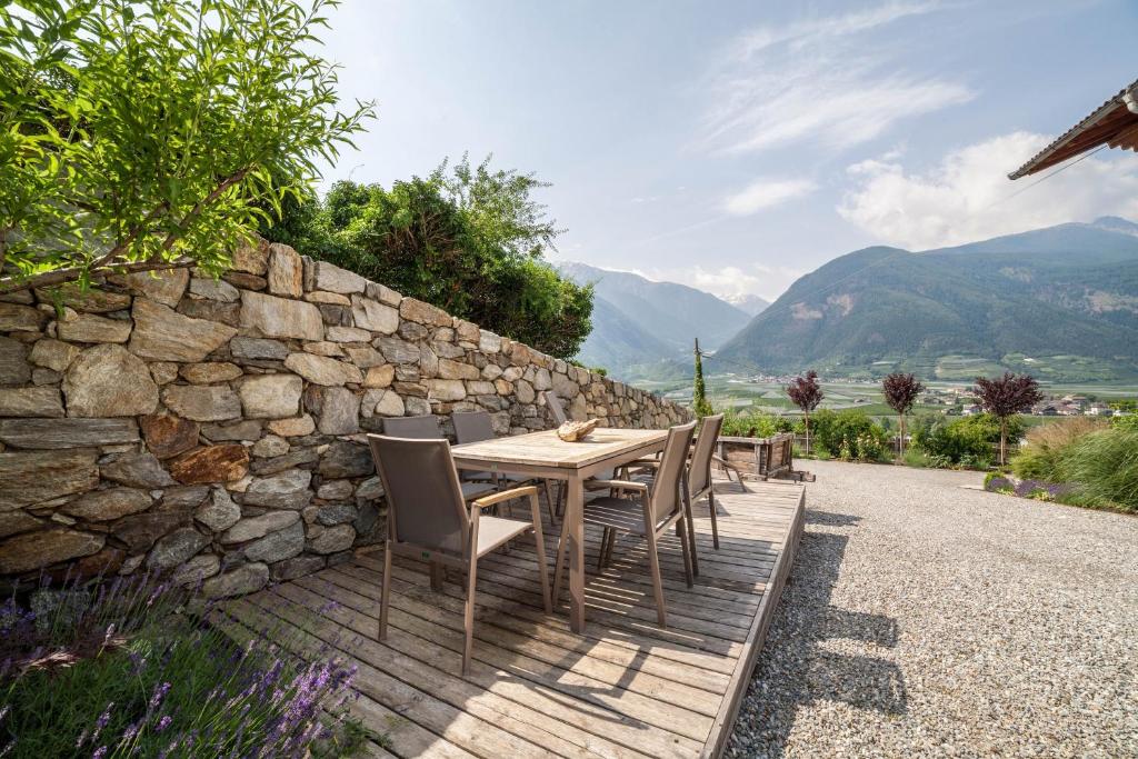 a wooden table with chairs and a stone wall at Langstein Wohnung Lavendel in Coldrano