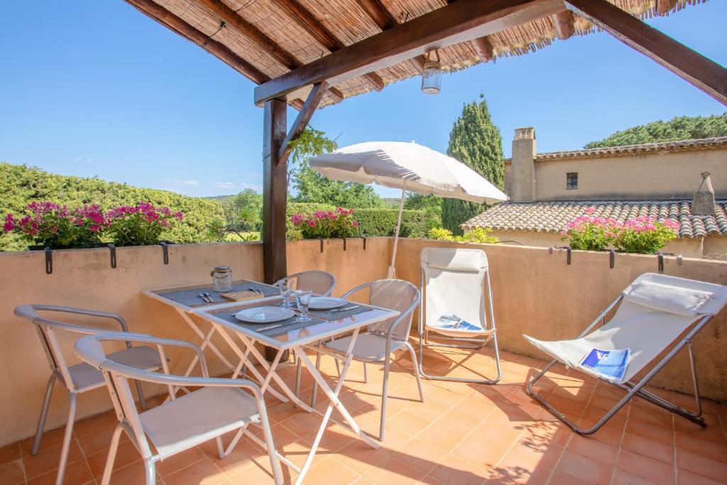 a patio with a table and chairs and an umbrella at Studio Le Val de Pons Ramatuelle in Ramatuelle