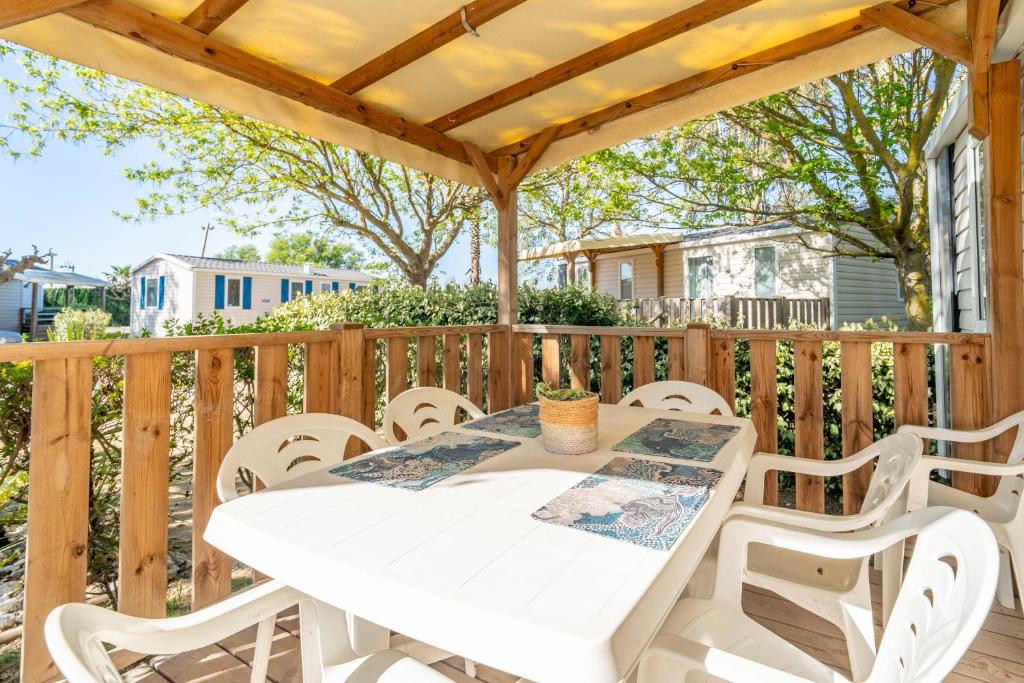 a white table and chairs on a wooden deck at Mobilhomelaco34 in Vendres
