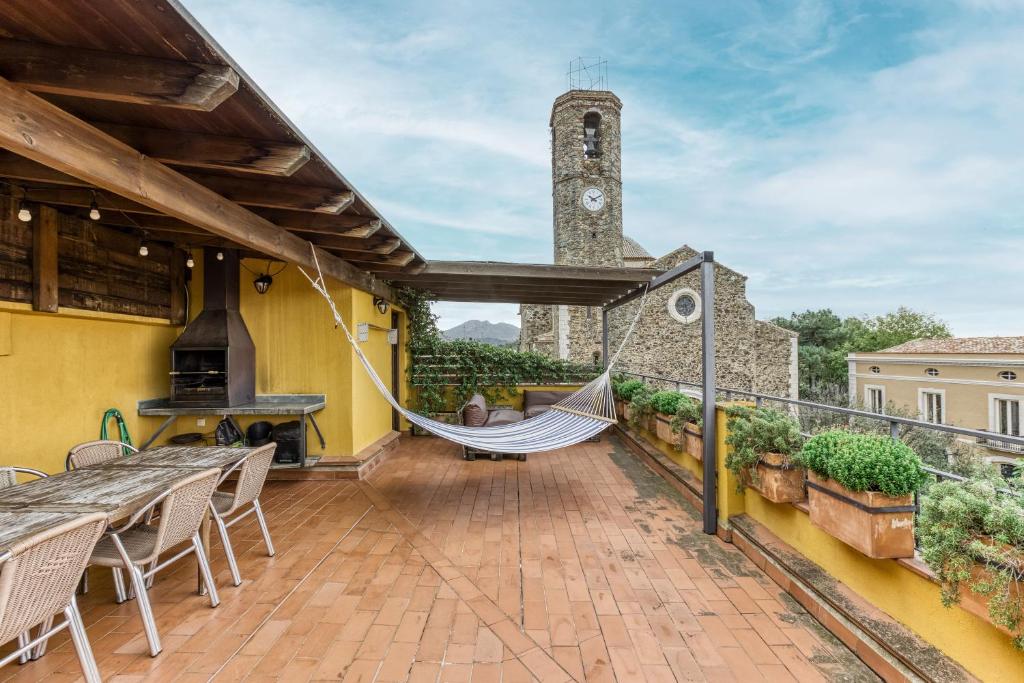 an outdoor patio with a hammock and a clock tower at Casa Rural El Torn in Garriguella