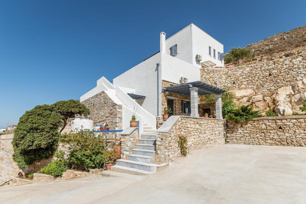 a house on the side of a stone wall at Vrahos Tinos in Panormos