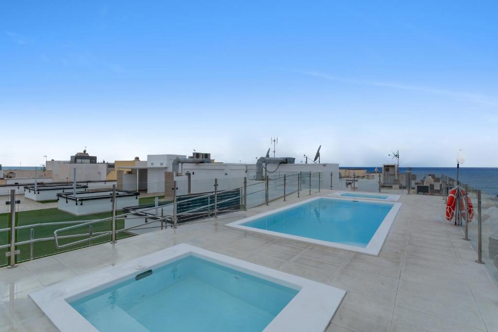 a swimming pool on top of a building with the ocean at Lupama Suite in Arguineguín