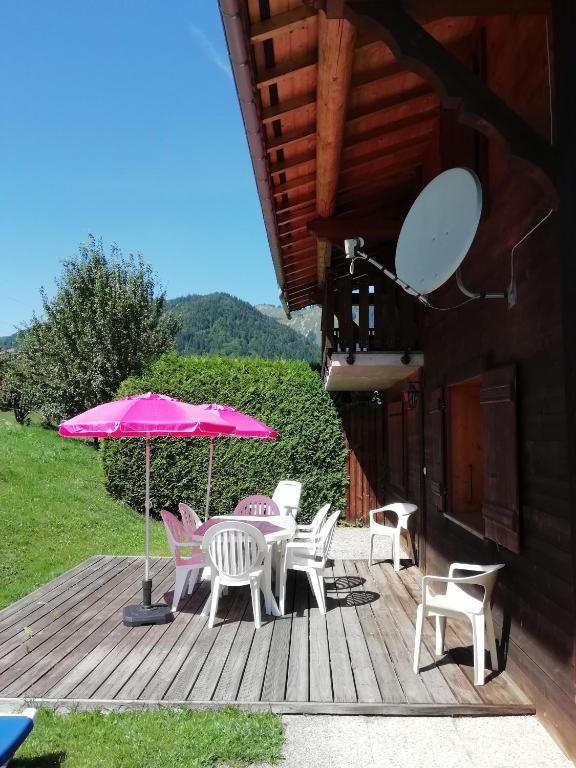 a deck with a table and chairs and an umbrella at Chalet 3 Etoiles - Le pèlouêt in Morzine