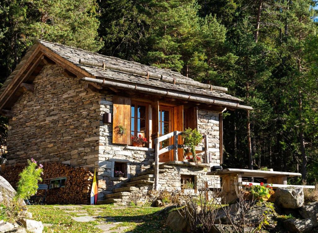 a small stone house in the middle of a forest at Chalet Atmosfera Res Albert in San Guglielmo