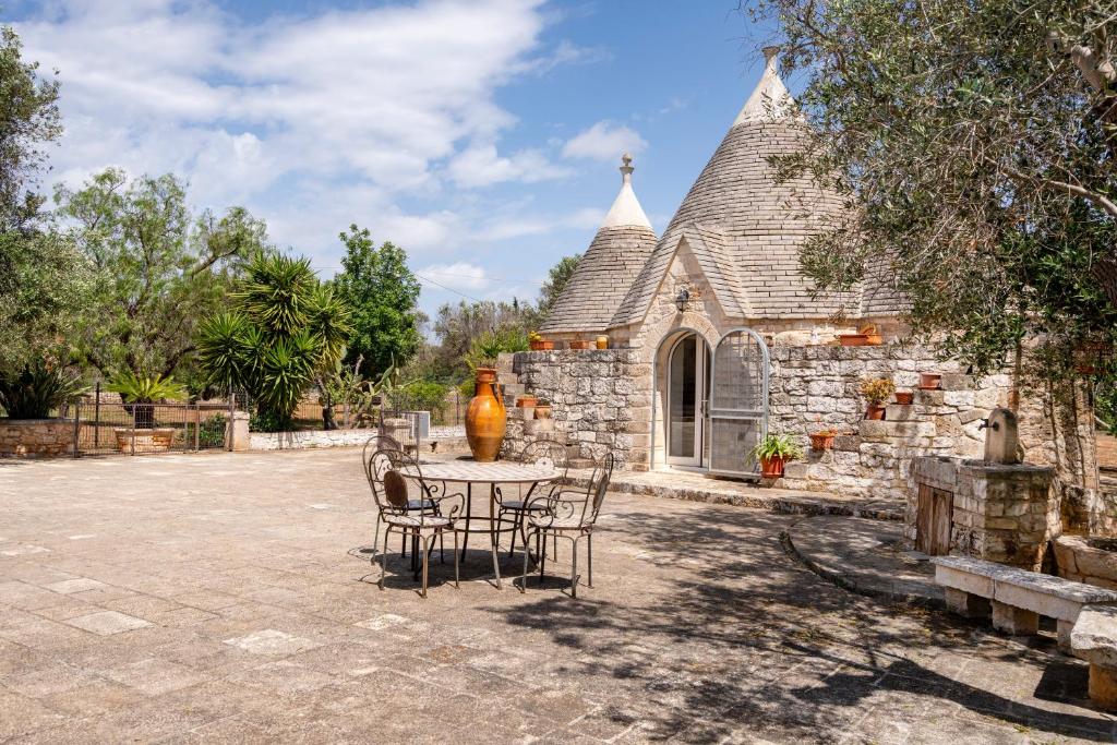 a table and chairs in front of a stone building at Villa Trullo Ulivo with pool in Carovigno