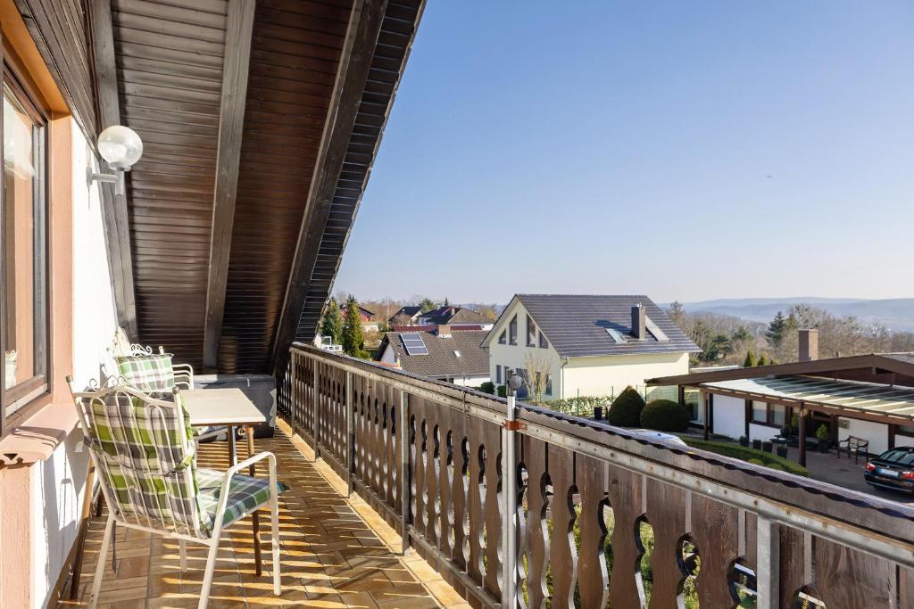 a balcony with a chair and a view of a city at Heidi's Panoramablick in Neuerode