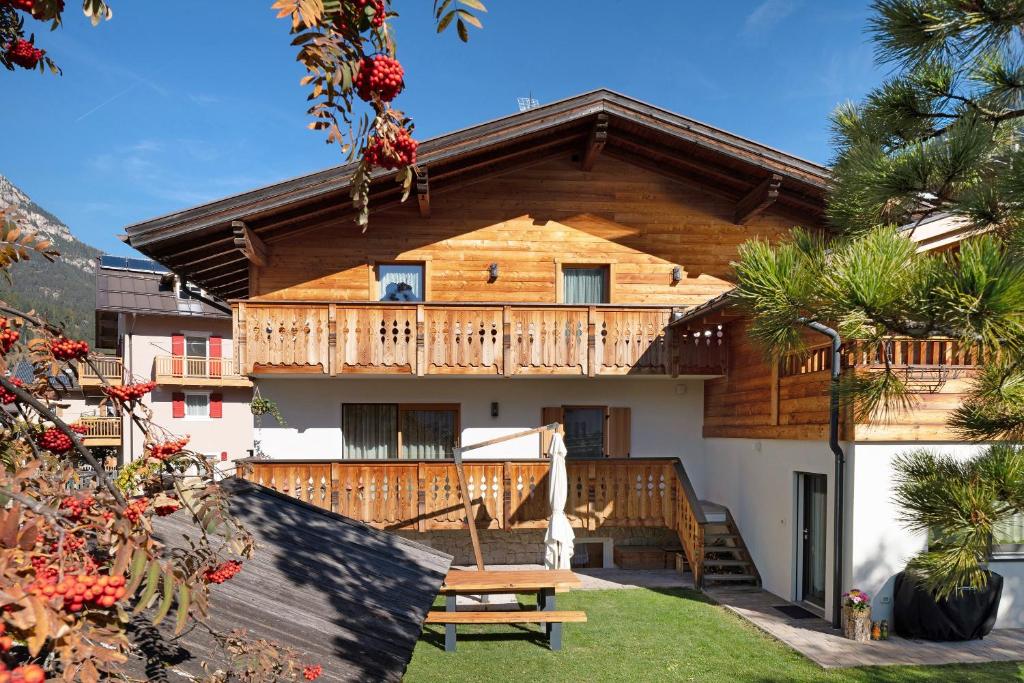 a wooden house with a deck and a bench at Ciasa Giorgina a Pozza di Fassa in Pozza di Fassa