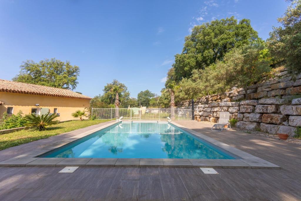 a swimming pool in a yard with a stone wall at Maison d'hôtes Collobrières in Collobrières