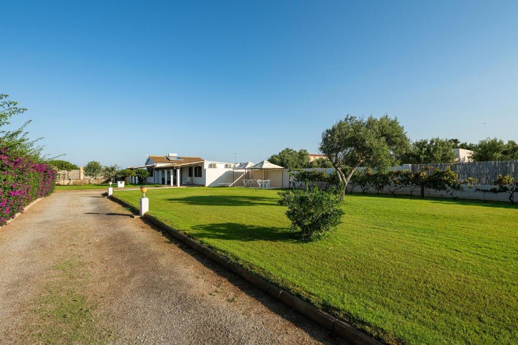 a grassy yard with a house in the background at Casa Silvia in Calasetta