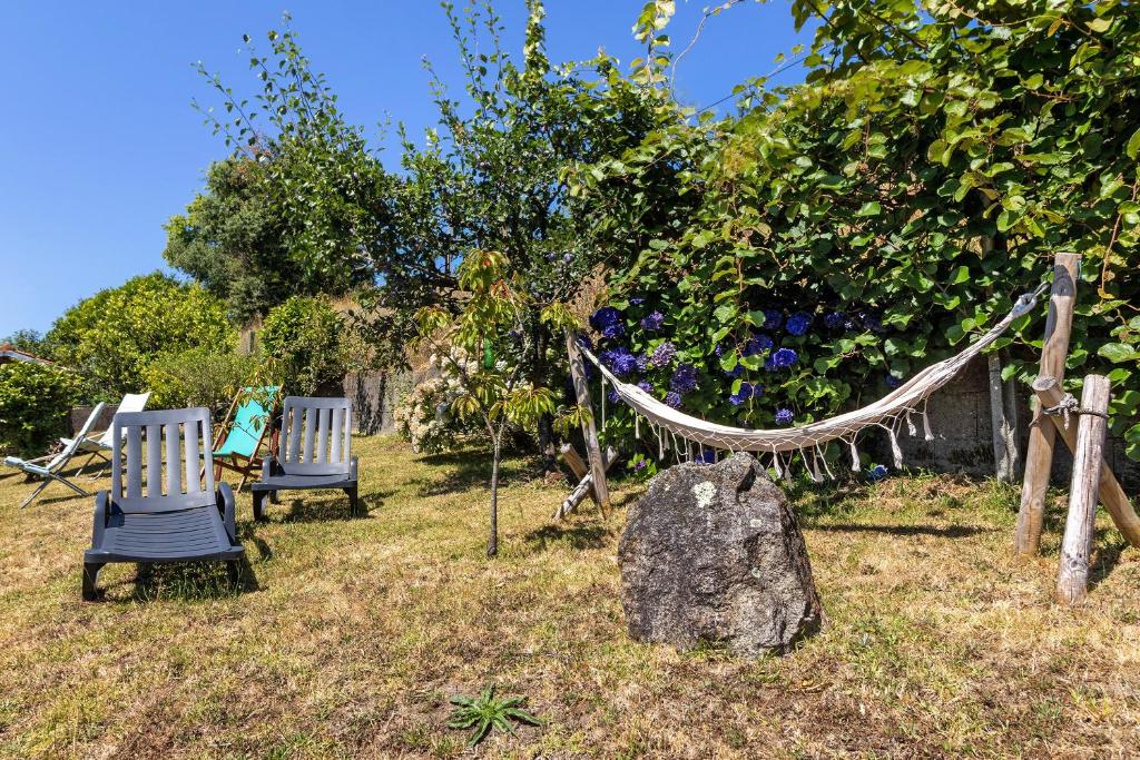 two chairs and a hammock in an apple tree at Casas do Natureza de Coura in Paredes de Coura