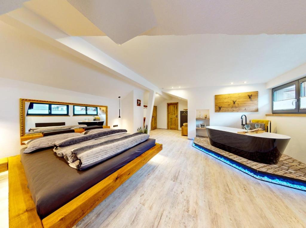 a large bedroom with a large bed and a bath tub at Apart Hennewinkl in Oetz