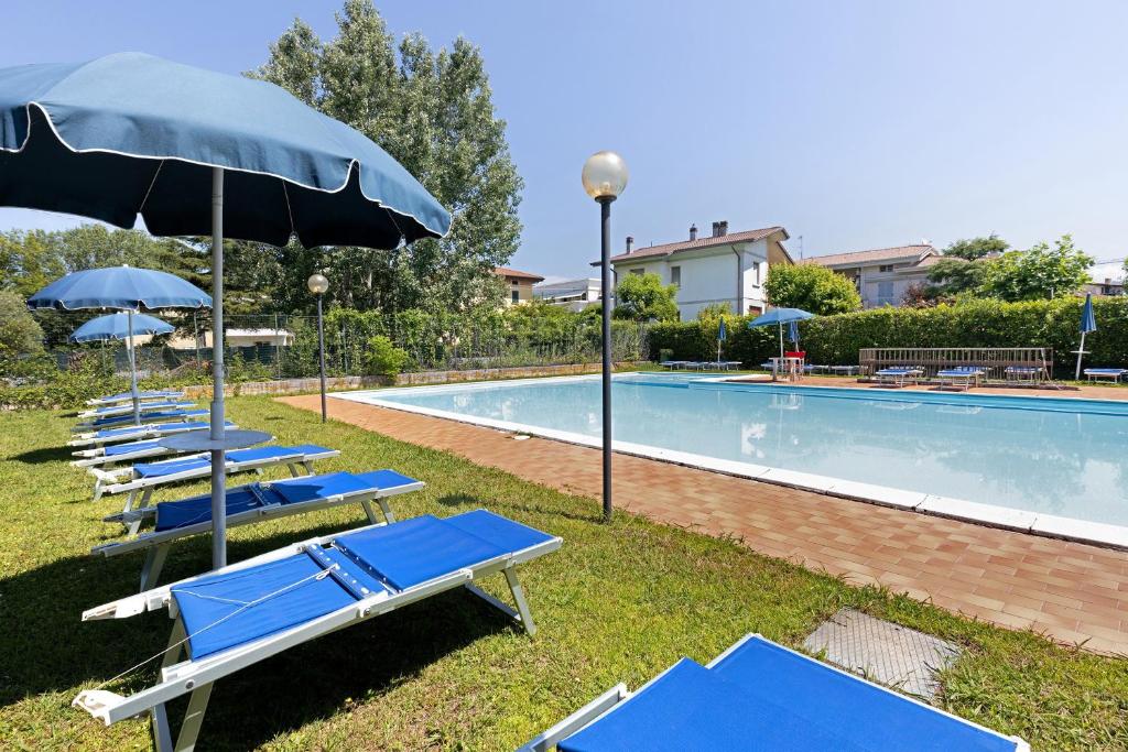 a row of blue chairs and umbrellas next to a swimming pool at Brezza del lago in Desenzano del Garda