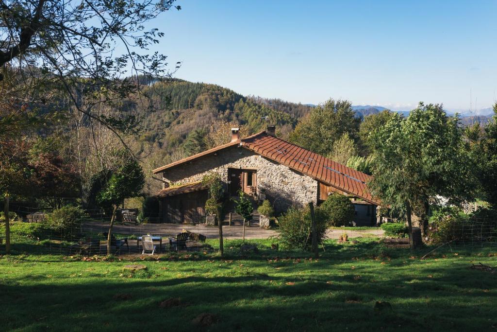 a house in a field with a mountain in the background at Pagorriaga in Beasain