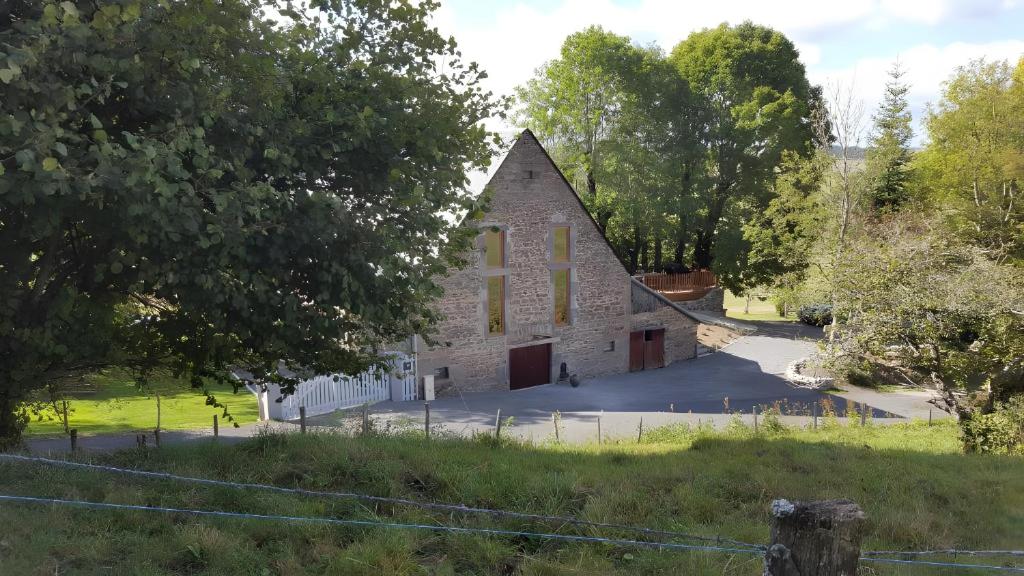 an old stone church in a field with trees at La Trouverie in Laqueuille