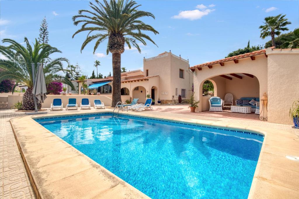 a swimming pool in a villa with palm trees at Villa Shalimar Moraira in Teulada