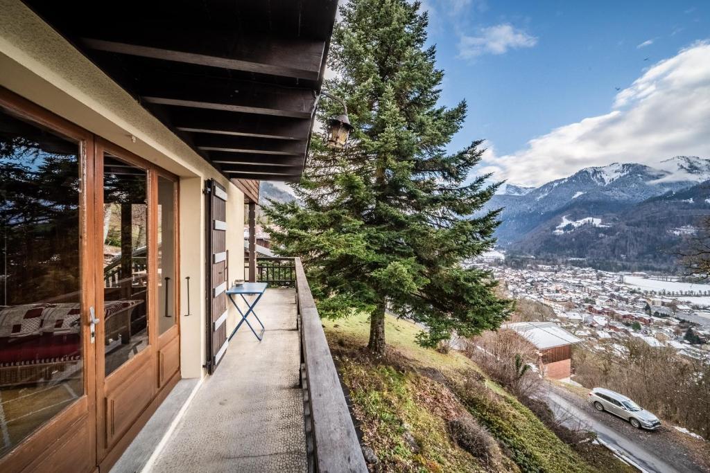 a porch of a house with a tree and mountains at Chalet Franclair in Samoëns