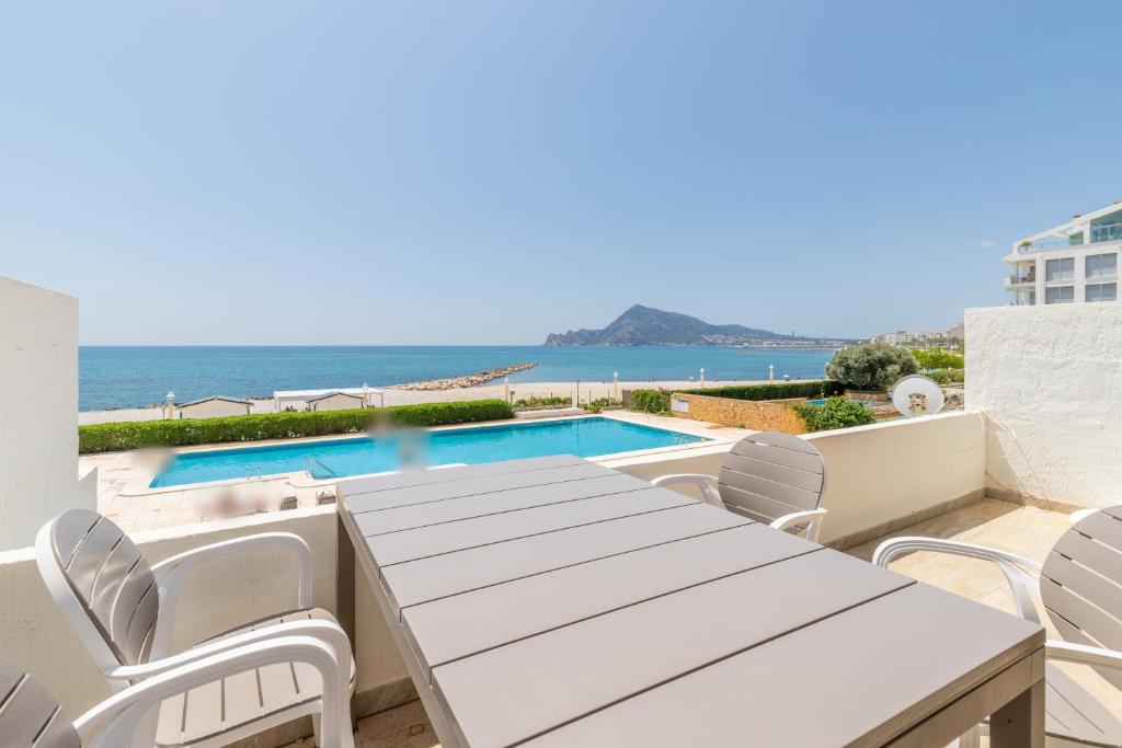 a patio with a table and chairs and a swimming pool at Top first line apartment Altea in Altea