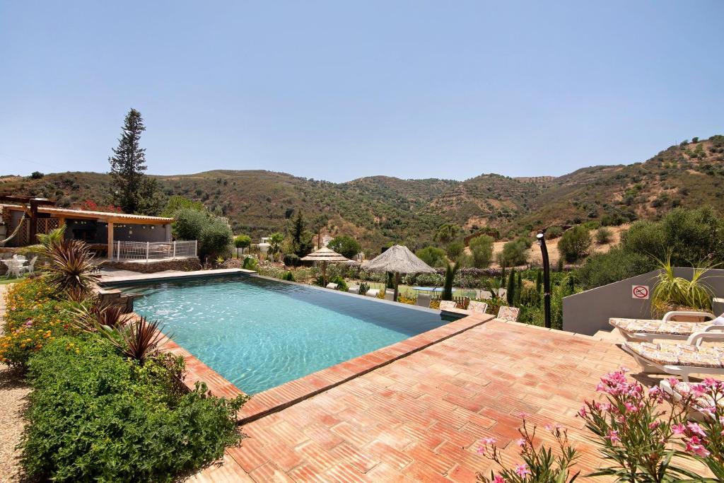 a swimming pool in a yard with mountains in the background at Quinta do Silêncio T4 in Tavira