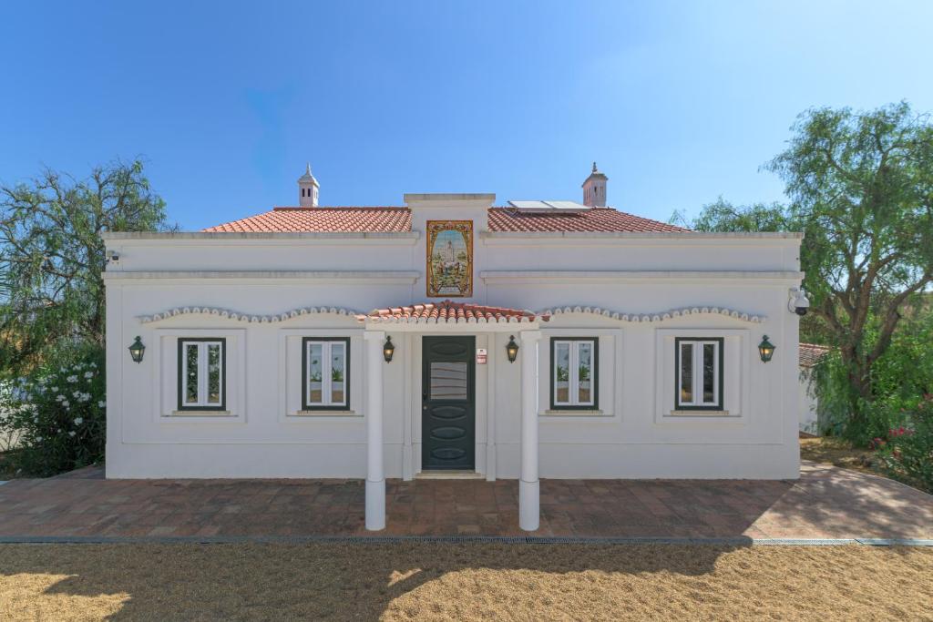 a large white house with a black door at Herdade da Tamanqueira in Pomar