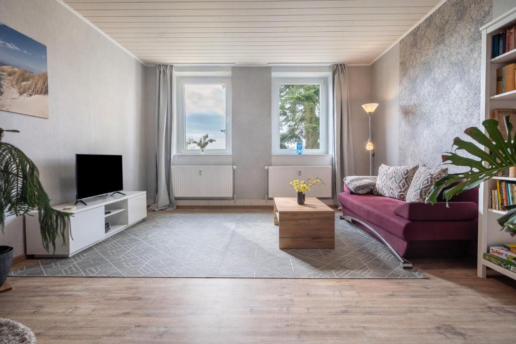 a living room with a purple couch and a tv at Landglück in Hohenmocker