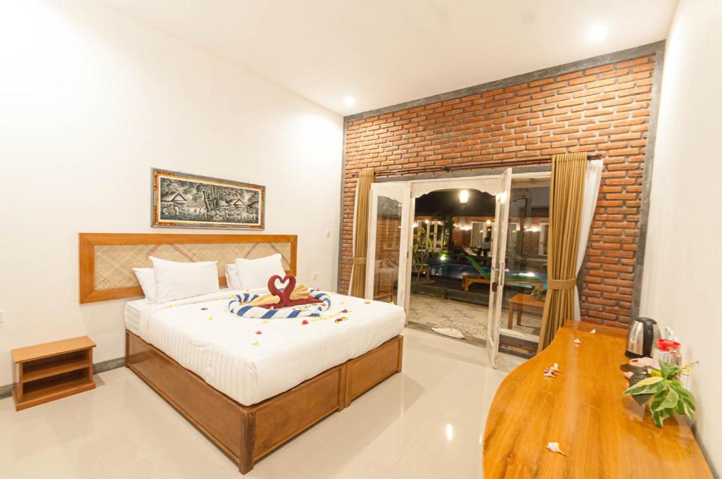 a bedroom with a bed and a brick wall at Rumah Gajah by Kubukubali in Pemuteran