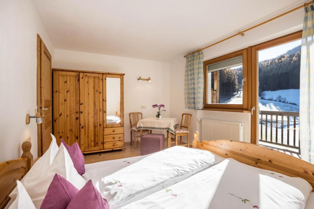 a bedroom with a bed and a balcony with a table at Bnb Lettnerhof Balcony Family Suite in Monguelfo