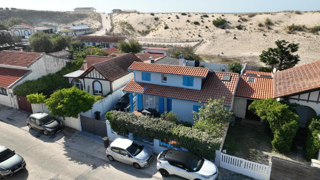 a blue house with cars parked in a parking lot at Villa 16 personnes à 50m plage Sud in Lacanau