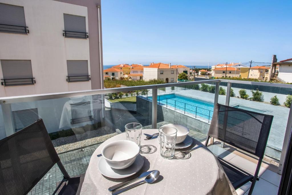 a dining table with a view of the pool on a balcony at Apartment Beach Waves Home in Nazaré