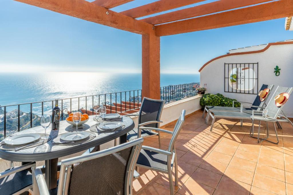 a balcony with a table and chairs and the ocean at 180-degrees sea view with pool in Benitachell