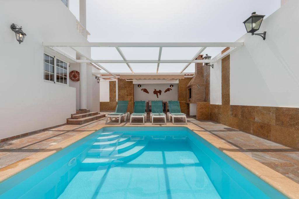 a swimming pool with two chairs and a pool house at La Villa in Tarajalejo