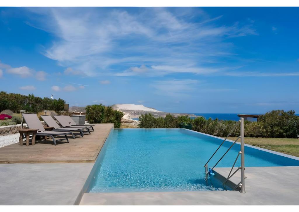 a pool with chairs and the ocean in the background at Luna Rossa Milos - Olive Home in Provatas