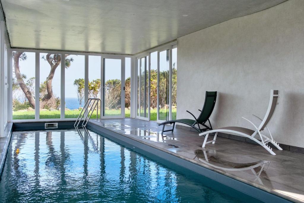 a house with a swimming pool with two chairs at Rocha do Mar 2 in Biscoitos