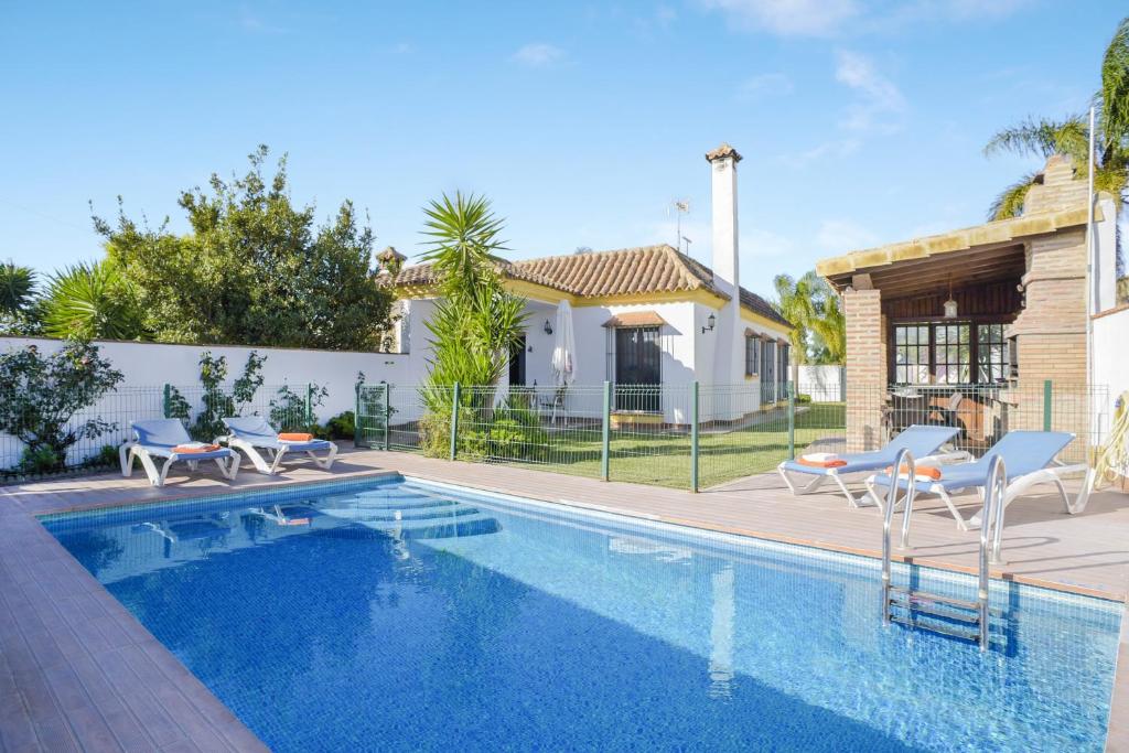 a swimming pool with chairs and a house at Casa Villanueva 2 - Sólo Familias in Conil de la Frontera