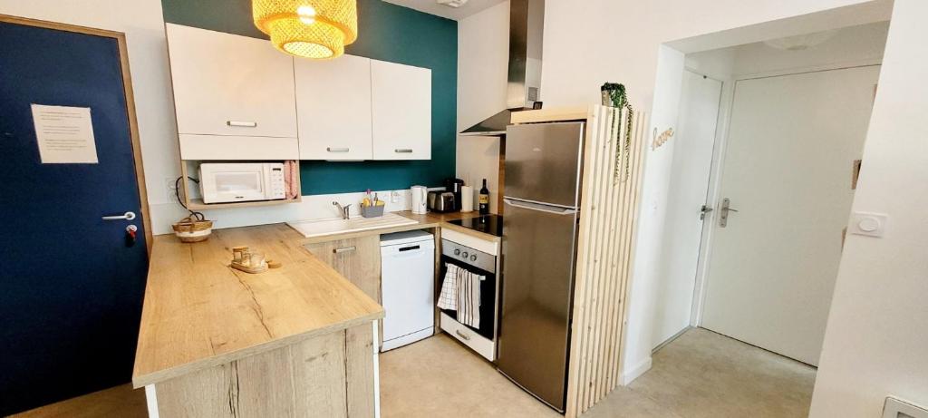 a kitchen with a stainless steel refrigerator and white cabinets at L'appartement De La Forêt in La Tranche-sur-Mer