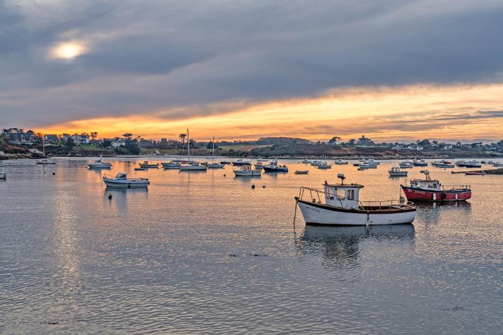 a group of boats sitting in the water at sunset at Ty Abéric maison en front de mer in Ploudalmézeau