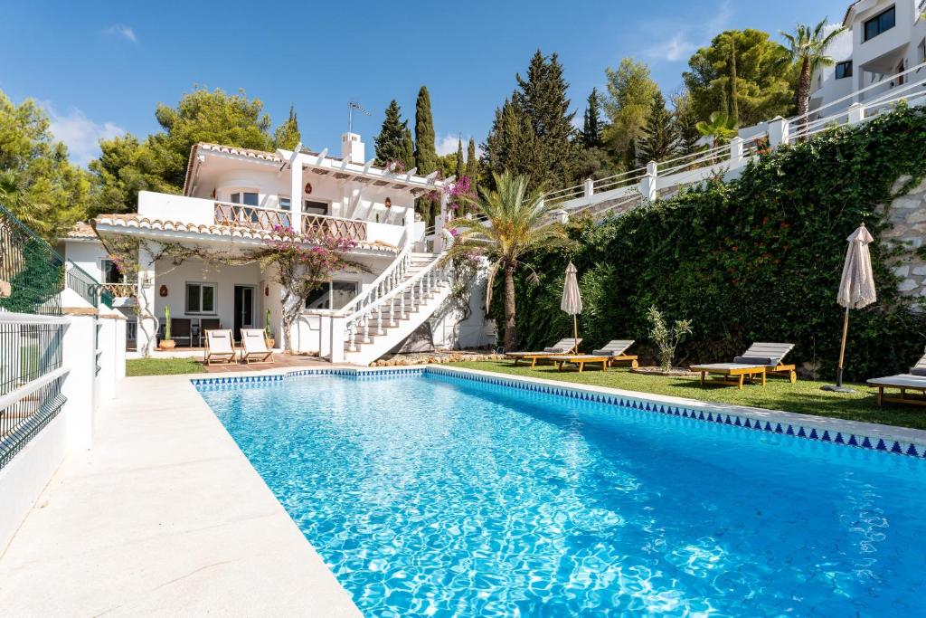 a villa with a swimming pool in front of a house at Casa Rocas in Mijas
