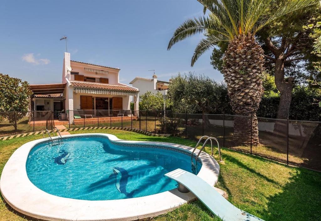a swimming pool in the yard of a house with a palm tree at Villa 100 m from the beach in Roda de Bará