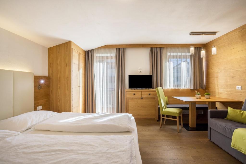 a hotel room with a bed and a table at Rosalpina Apt 1 in San Vigilio Di Marebbe