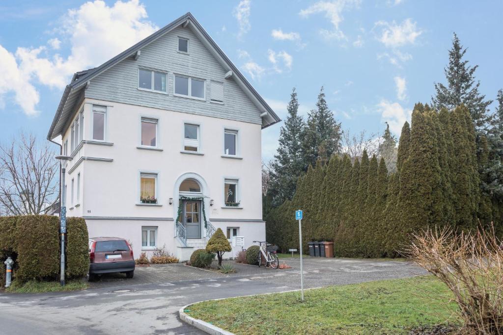 a white house with a car parked in the driveway at Ferienwohnung Tasoli in Lindau