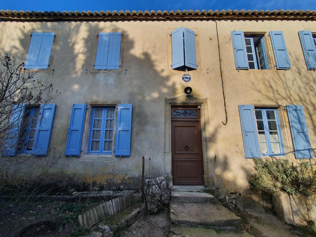 a house with blue shuttered windows and a door at Appartement Authentique Montaigut in Gissac