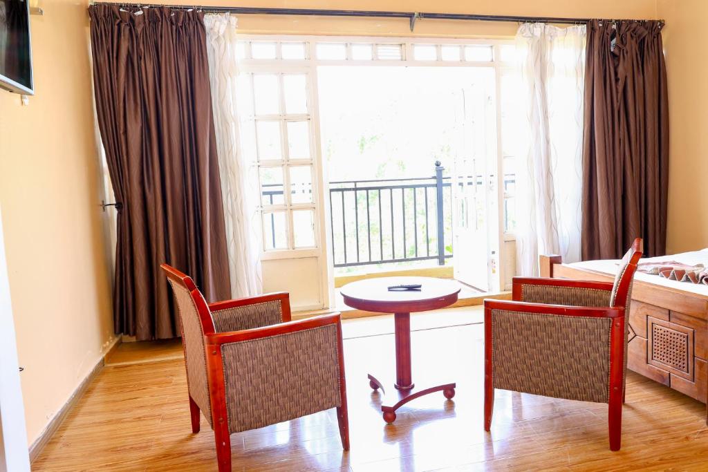a living room with a table and chairs and a window at Fairways Hotel in Narok