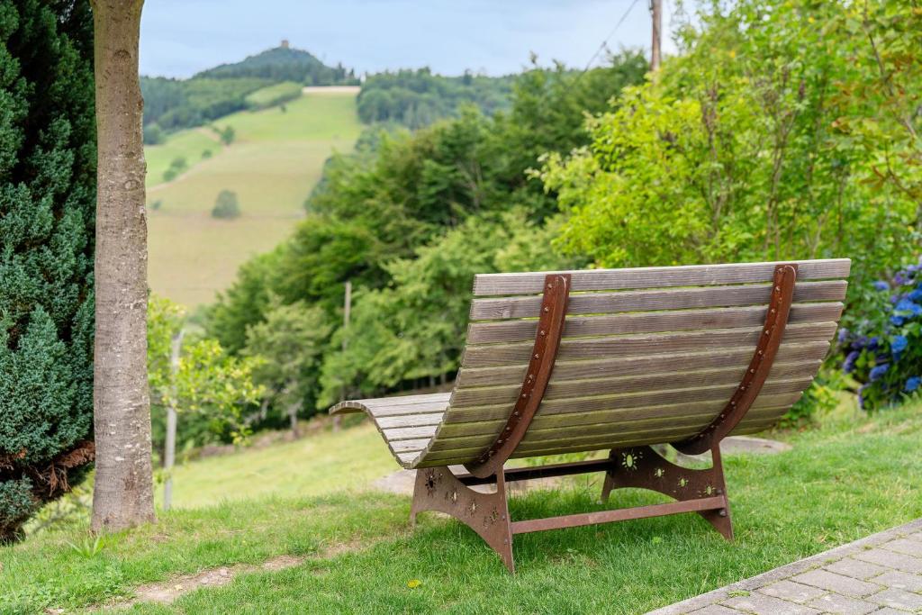 a wooden bench sitting in the grass near a tree at Ferienwohnung Burgblick in Biberach
