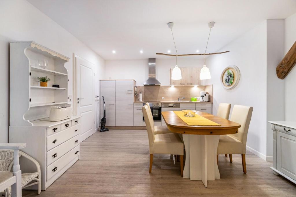 a kitchen with a wooden table and white cabinets at Haevn Erholung, Feuer, Wasser, Luft in Reußenköge