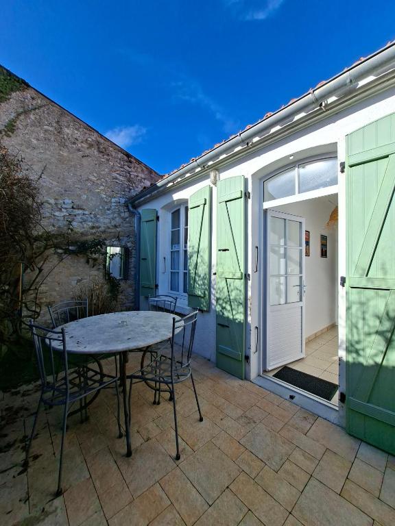 a patio with a table and chairs next to a building at L'instant Terrière,maison de charme in La Tranche-sur-Mer