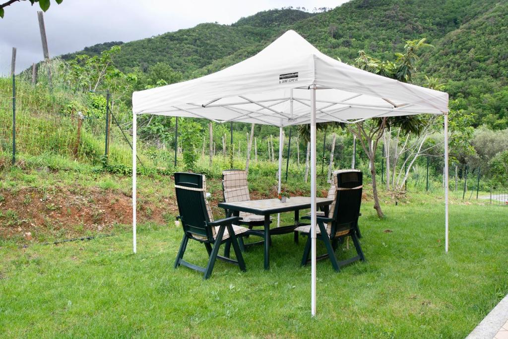 a table and chairs under a white umbrella at Il Frutteto 50 in Ortovero
