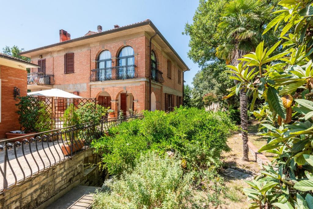 a brick house with a palm tree in front of it at Casa San Francesco Rapolano in Rapolano Terme